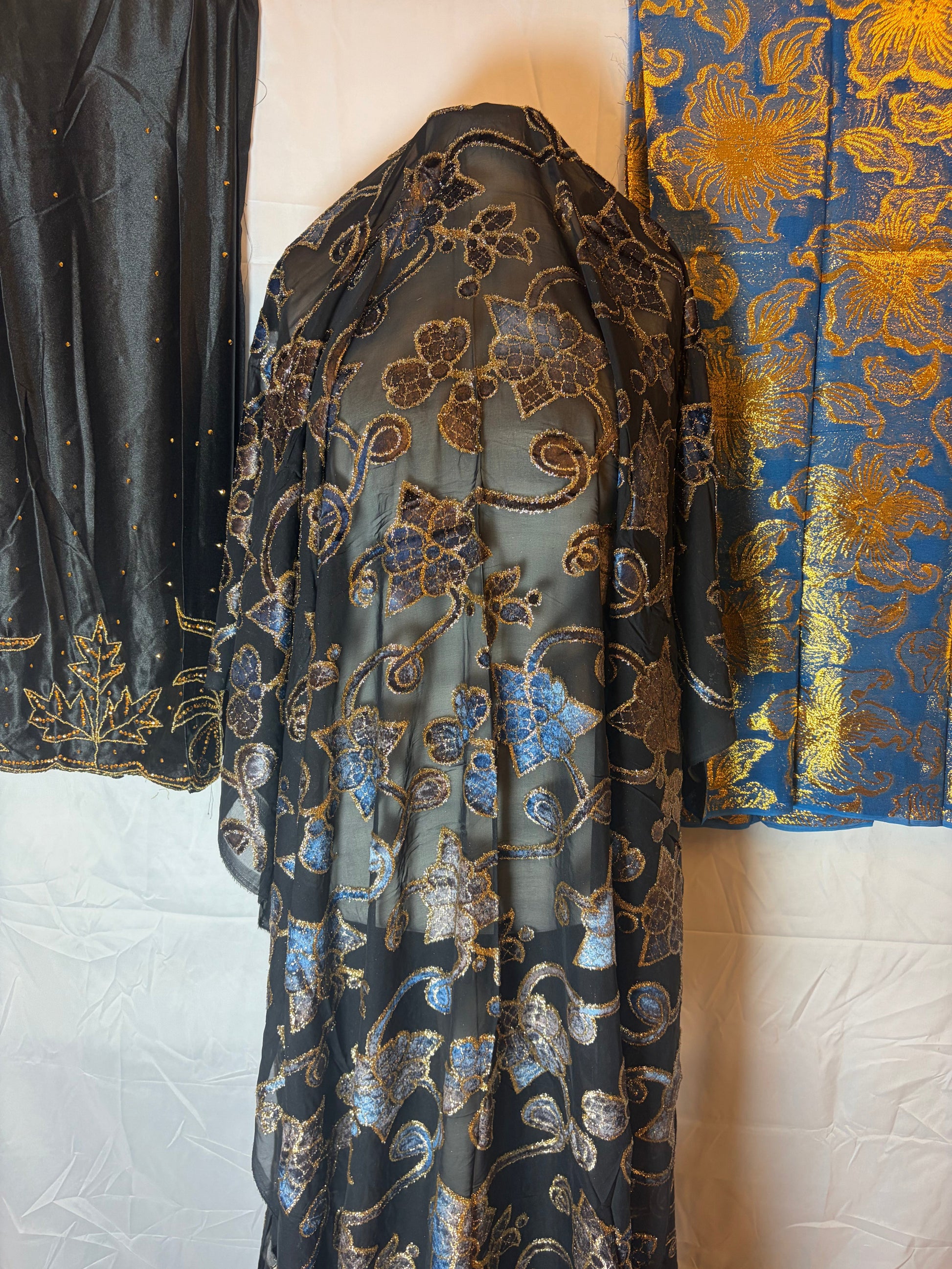 Floral patterned fabric draped over a mannequin with a blue and gold floral fabric in the background.