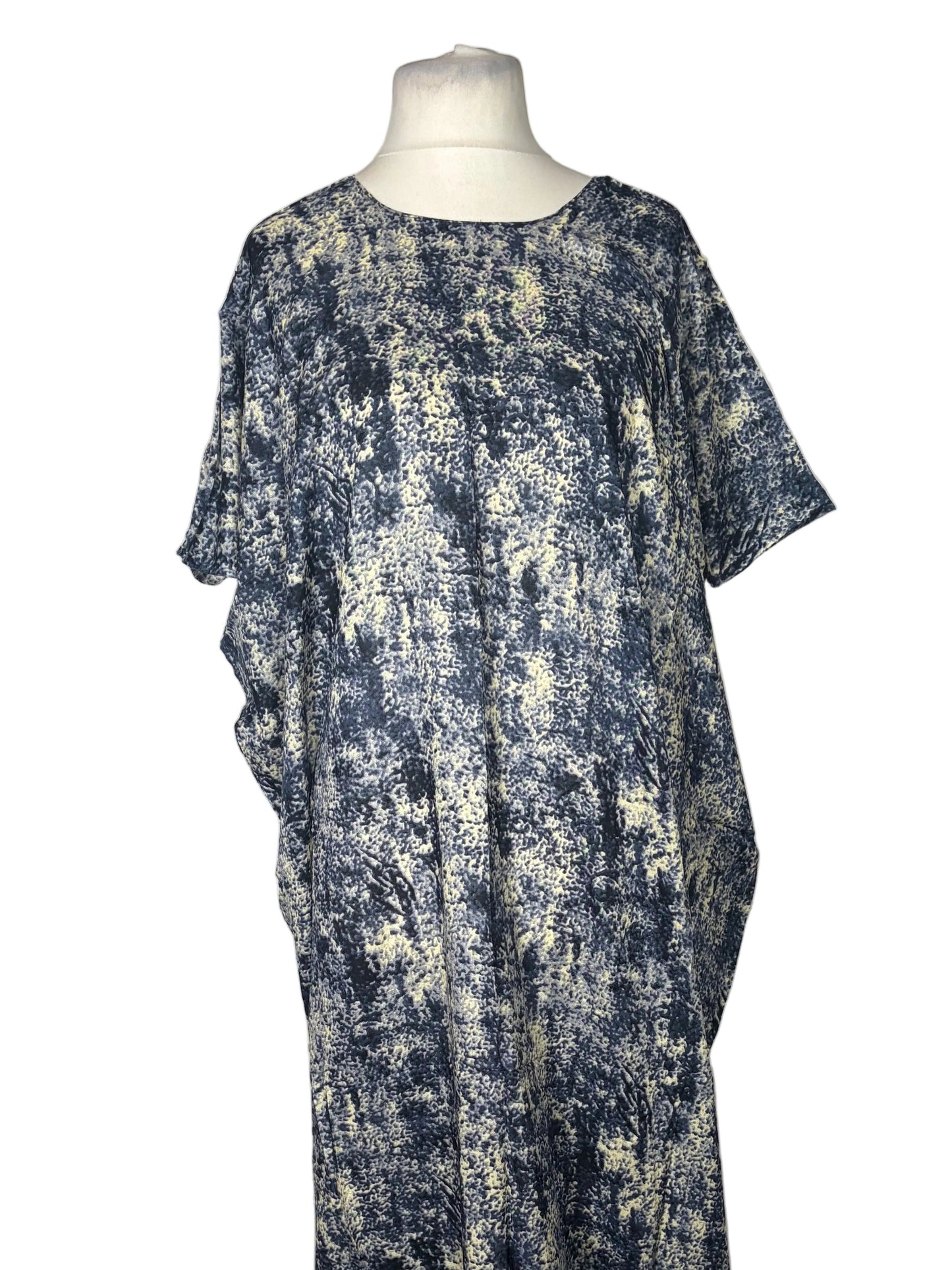 Mannequin wearing a blue and white patterned dress on a white bed.