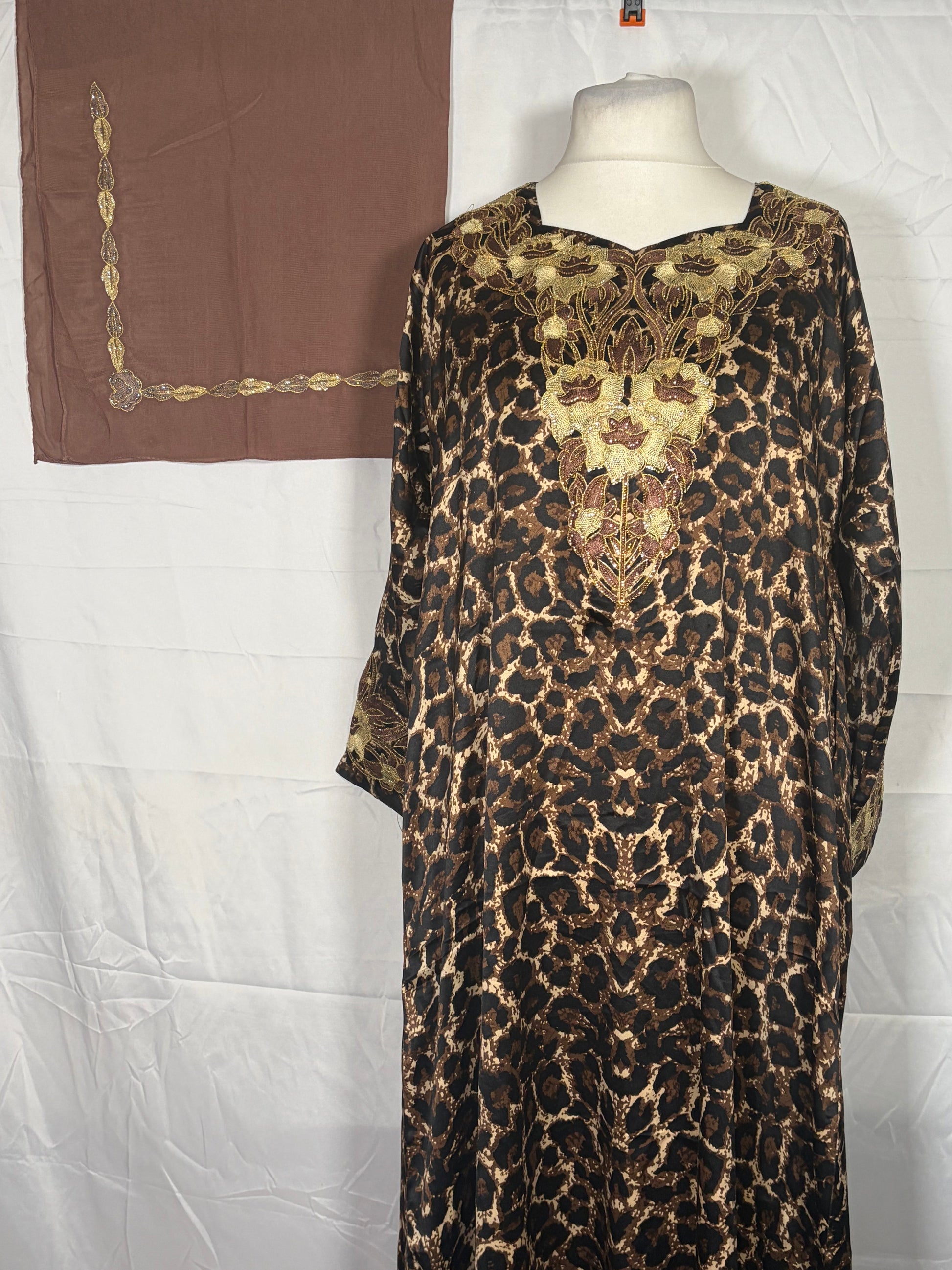 Leopard print Mukawarar dress on a mannequin with a brown fabric in the background