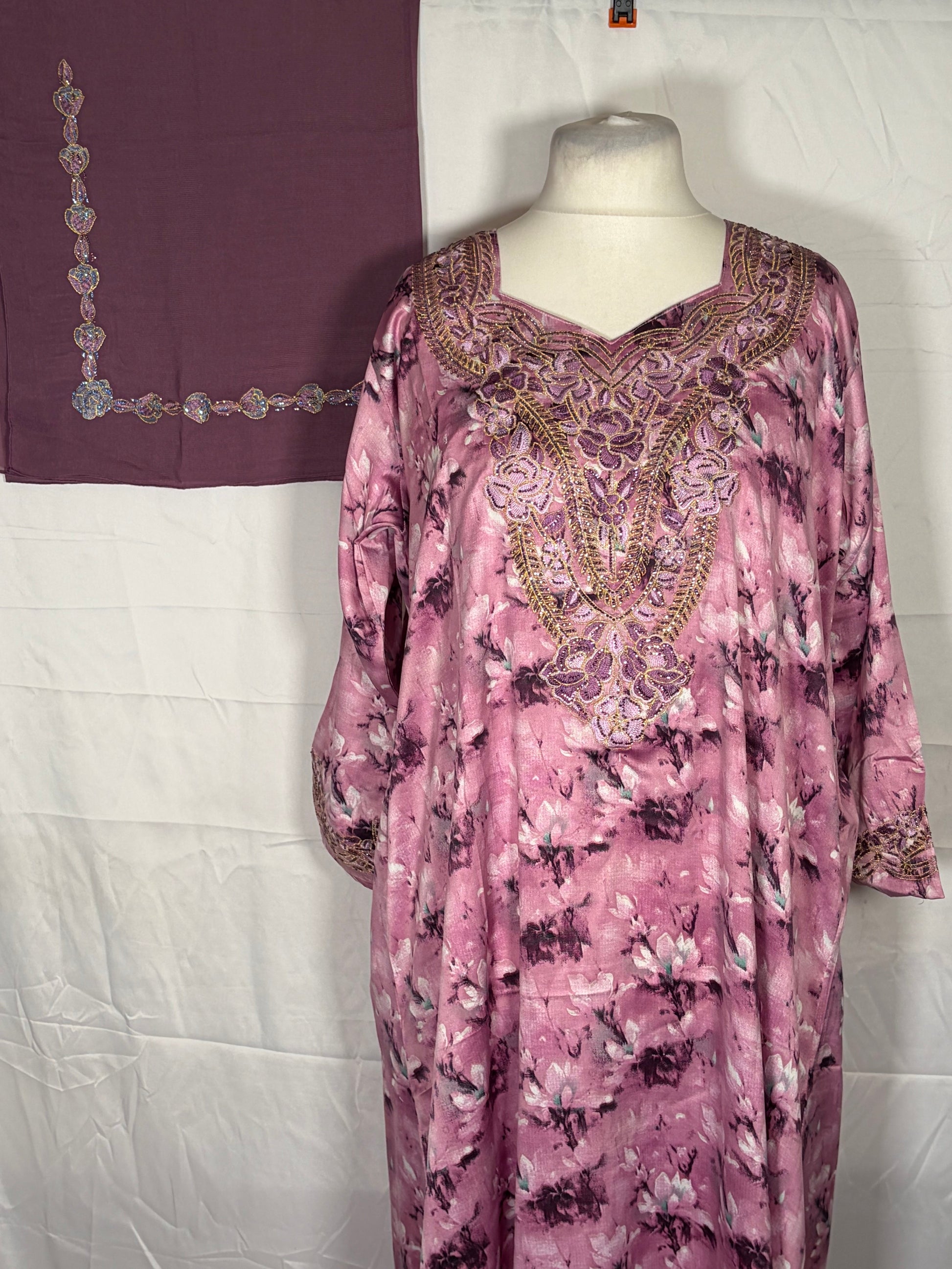 Pink floral Mukawarar dress with intricate embroidery on a mannequin against a white background