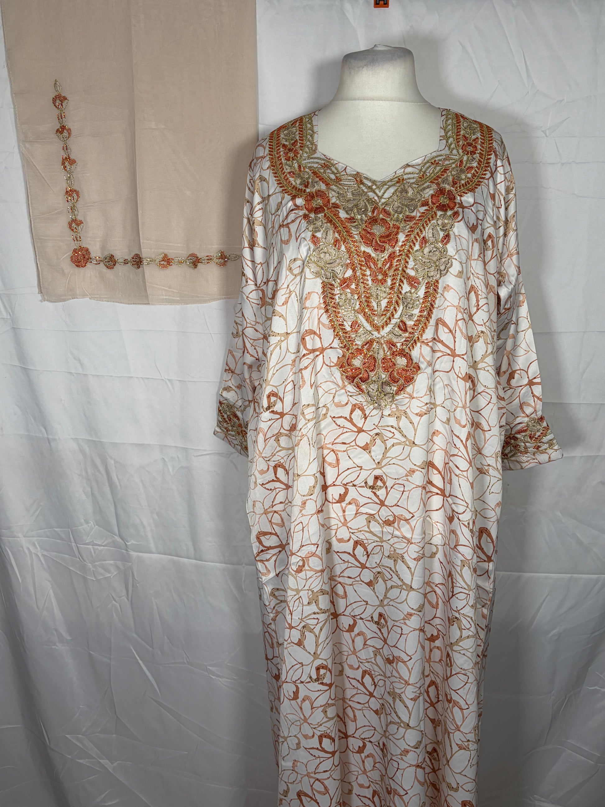 Embroidered Mukawarar dress on a mannequin with beige fabric in the background