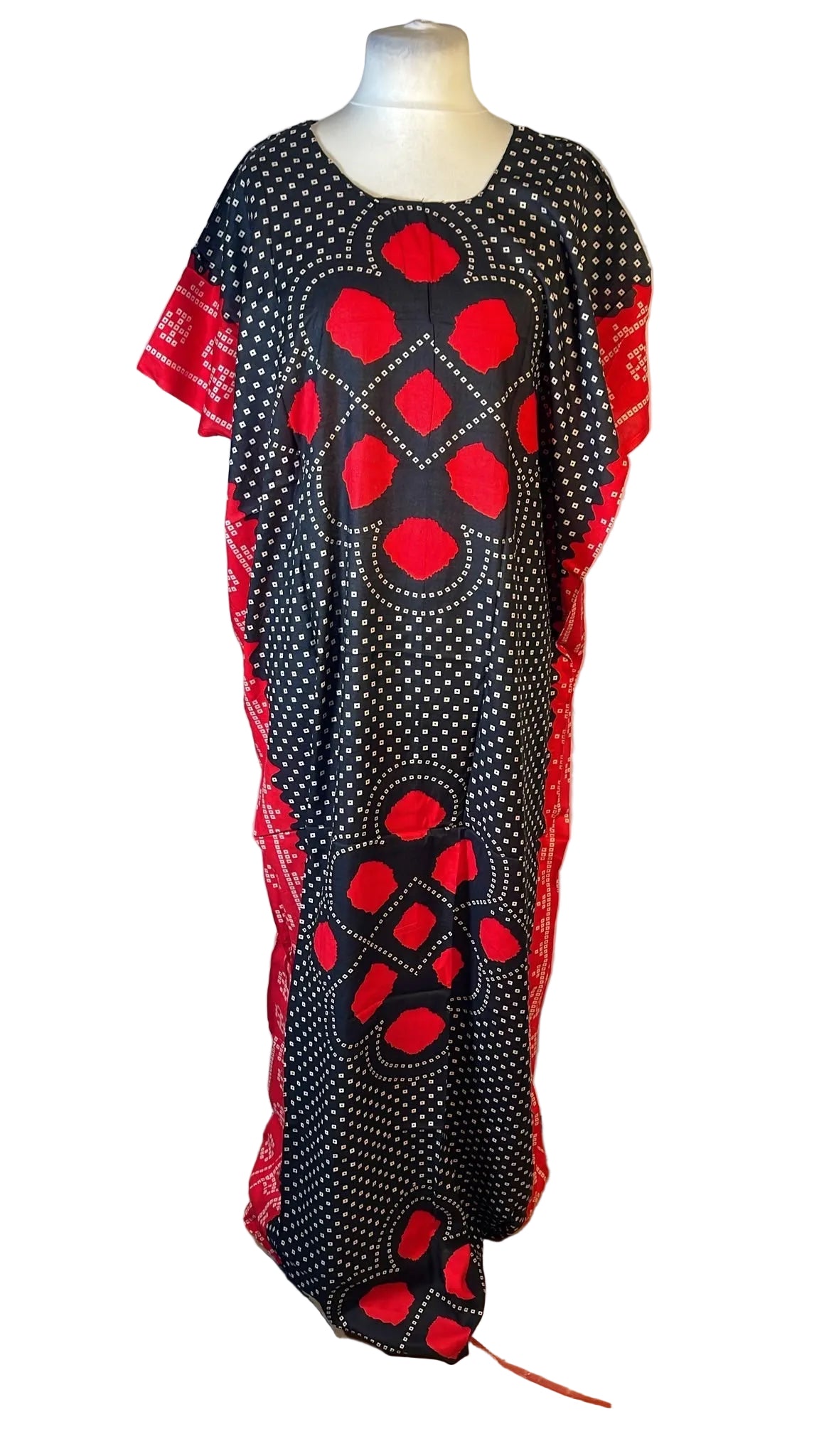 A black caftan dress with red and white patterns displayed on a mannequin against a white fabric backdrop.