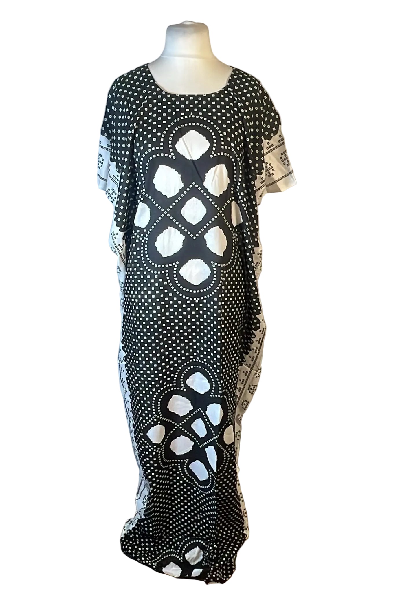 A black and white patterned kaftan dress displayed on a mannequin torso against a white fabric backdrop.