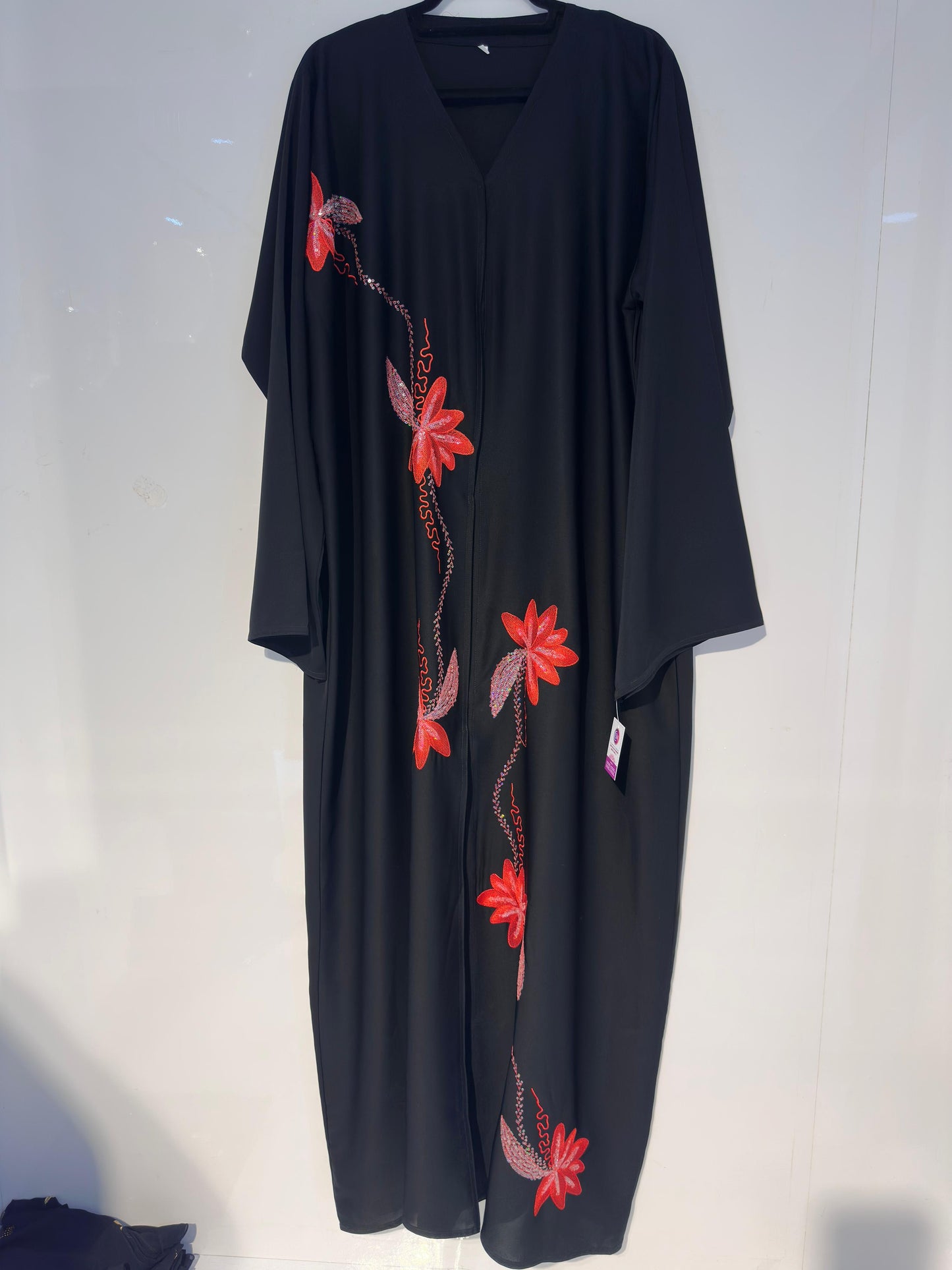 Black dress with red floral embroidery on a white background