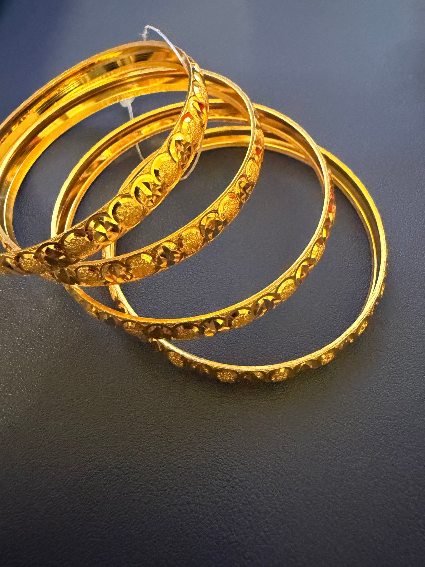 Set of gold bangles on a dark background