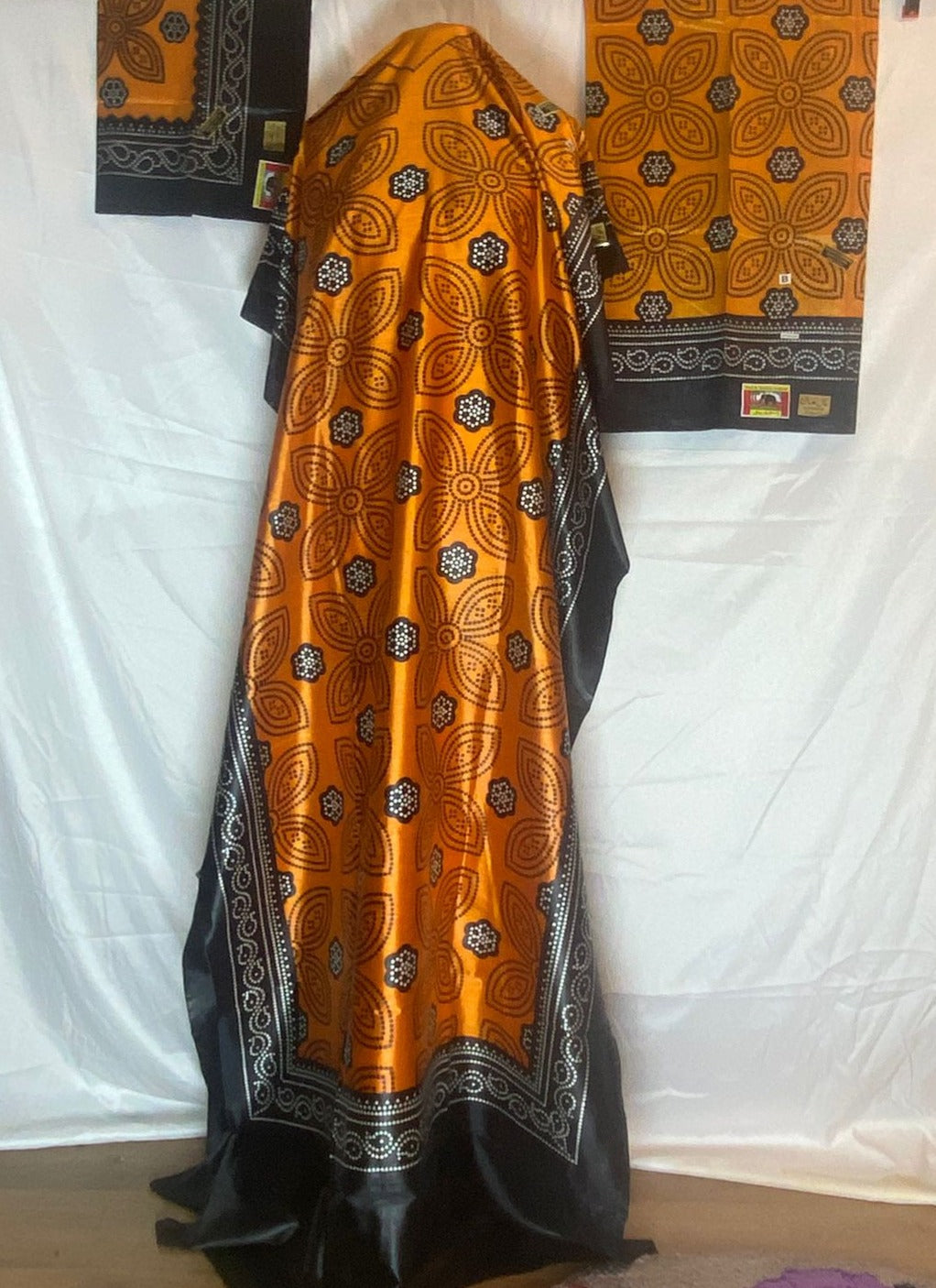 Orange and black patterned Somali Shaash fabric draped over a white background