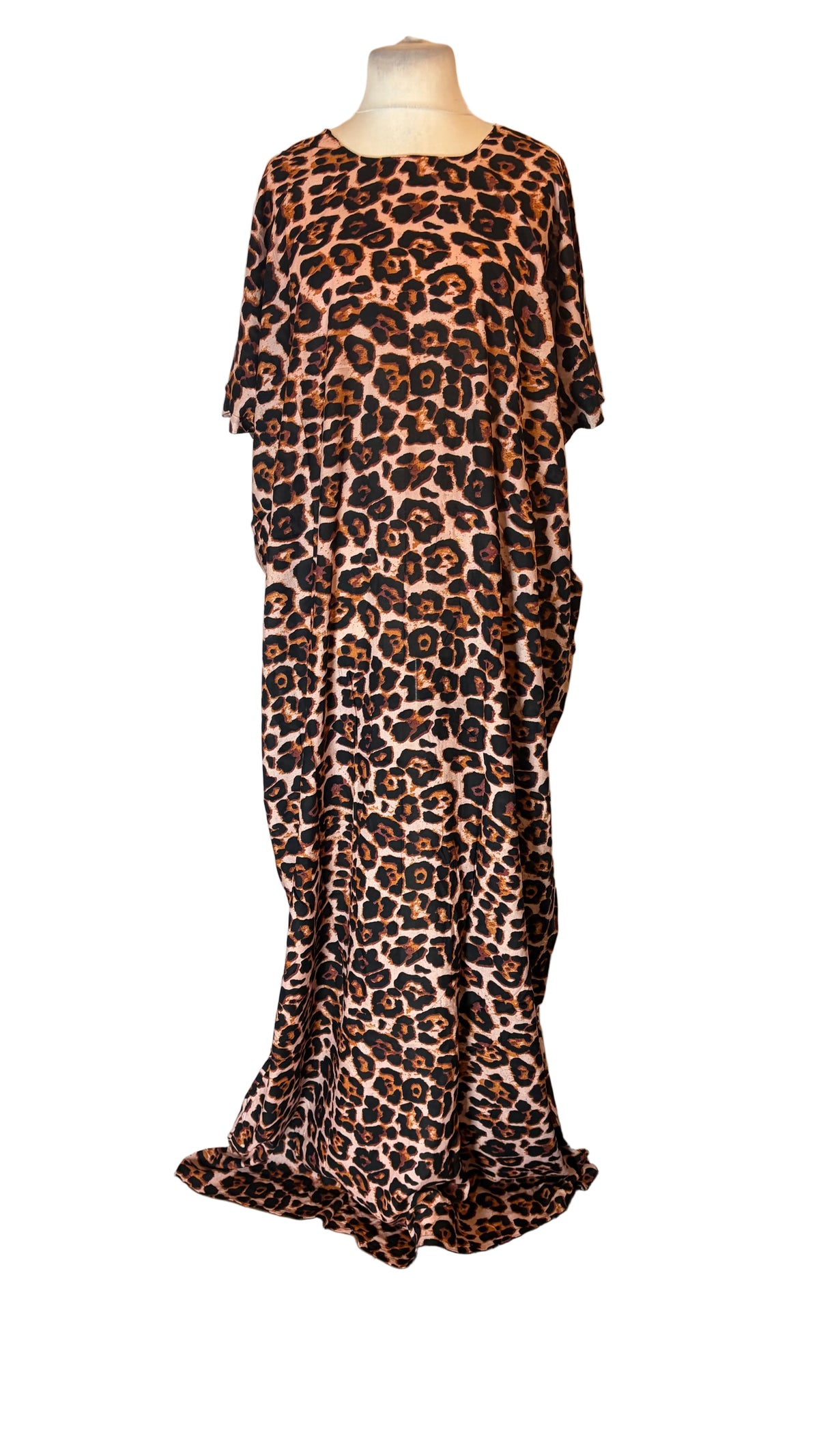 A leopard print Somali Baati dress displayed on a mannequin in front of a white fabric backdrop. The Somali Baati features a brown, black, and beige animal pattern with short wide sleeves and a loose, flowing silhouette.
