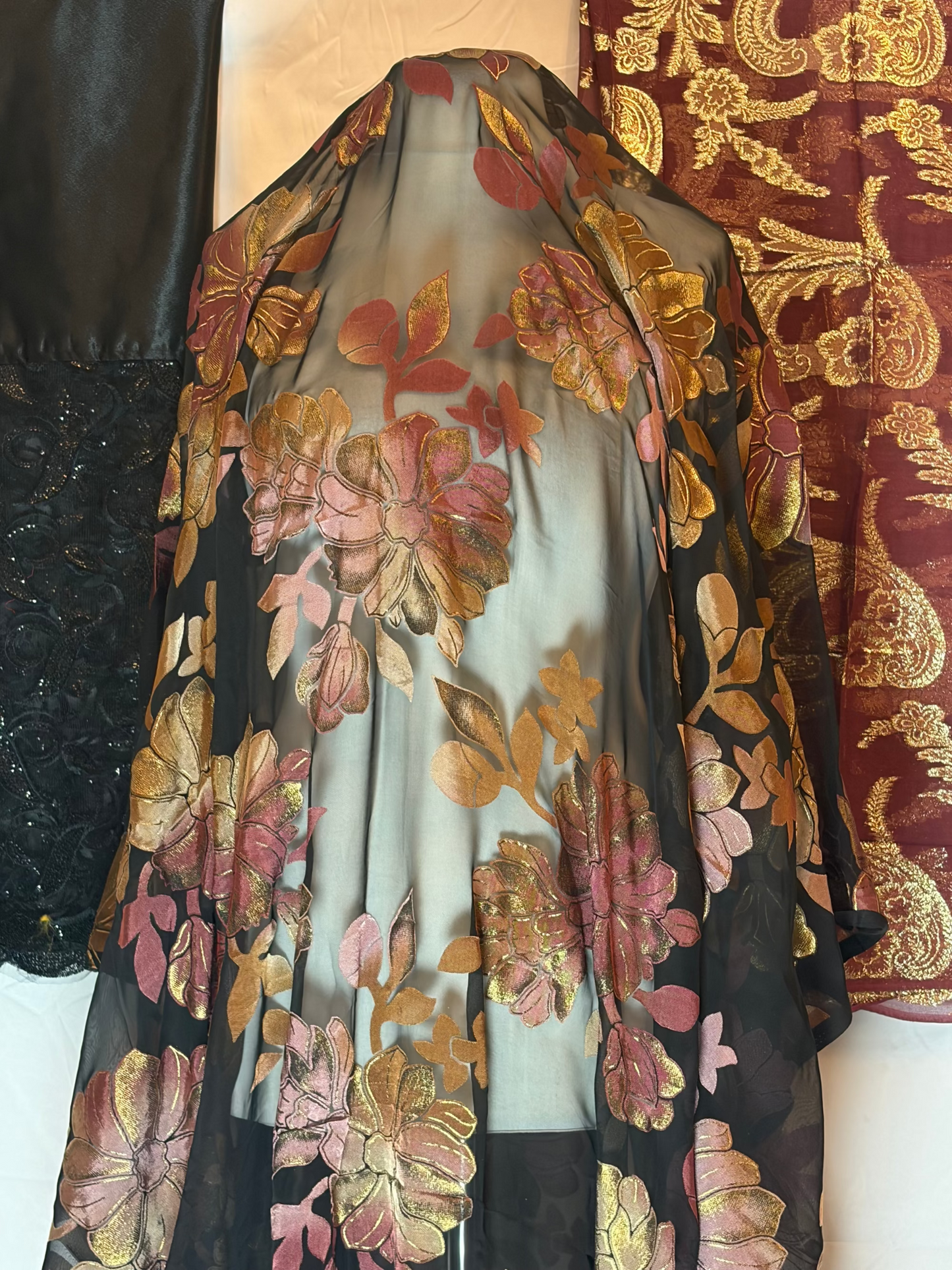 Floral embroidered sheer fabric on a mannequin against a patterned background