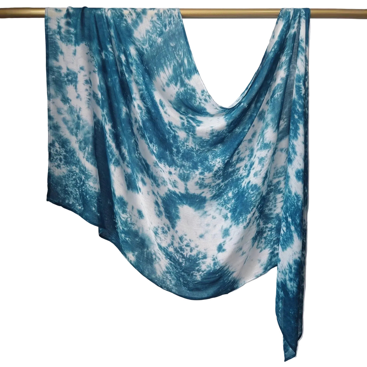 A lightweight fabric scarf or shawl with a blue and white tie-dye pattern, draped over a gold metal hanger against a white paneled wall.
