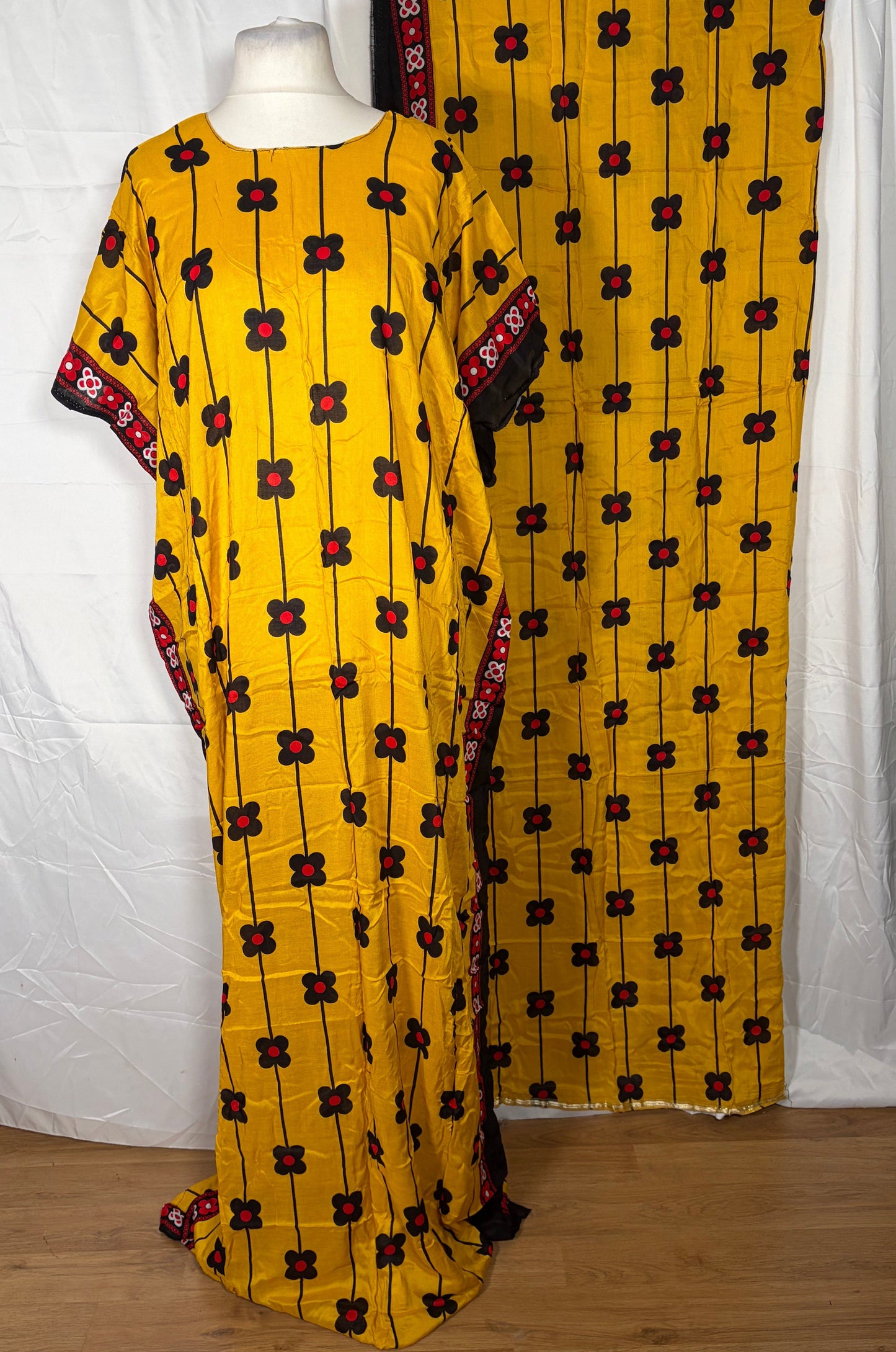 Yellow patterned fabric draped over a white surface with a wooden wall in the background.