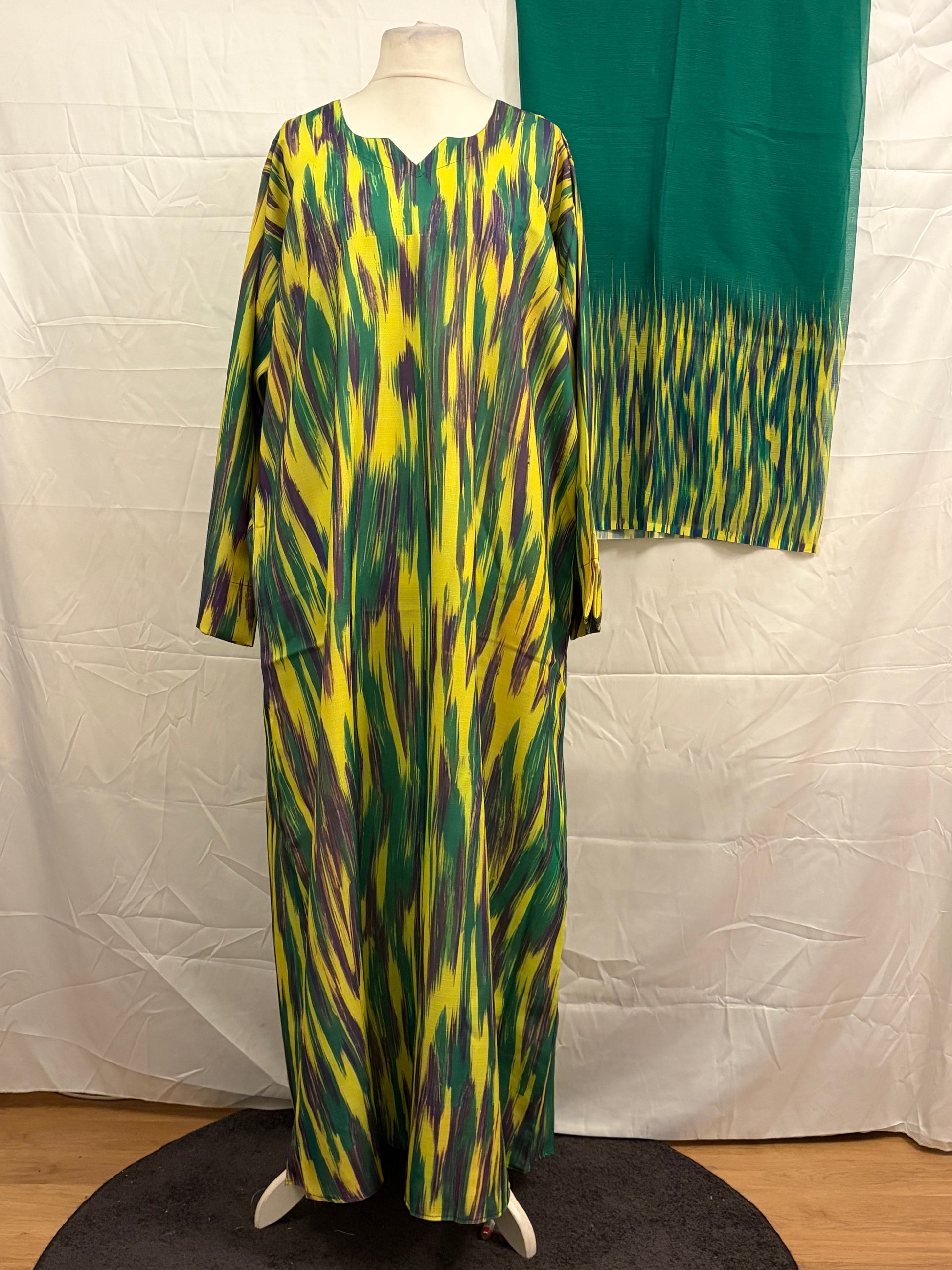 Mannequin wearing a colorful dress with a green and yellow pattern against a white background
