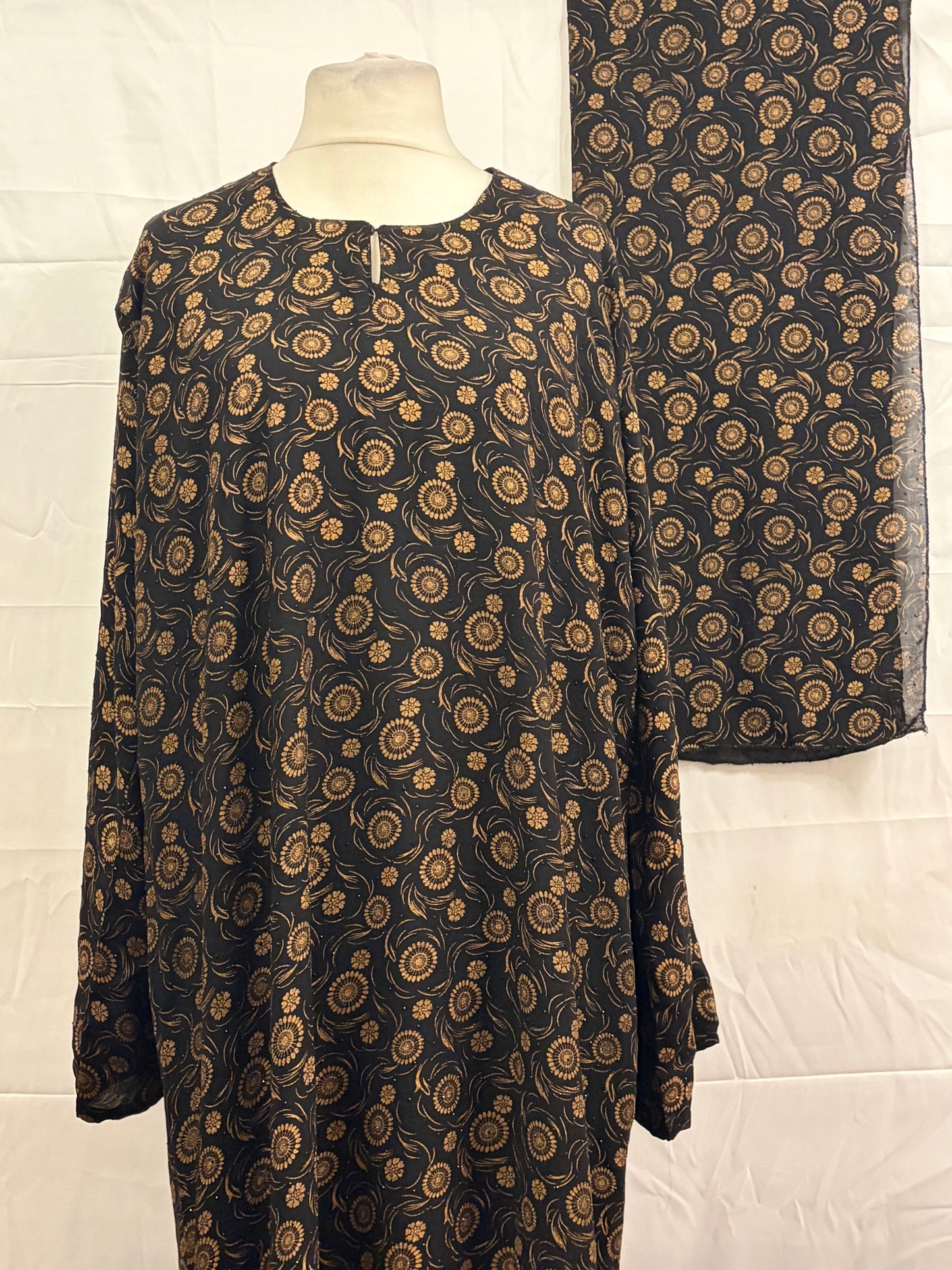 Black fabric with gold paisley pattern on a white background