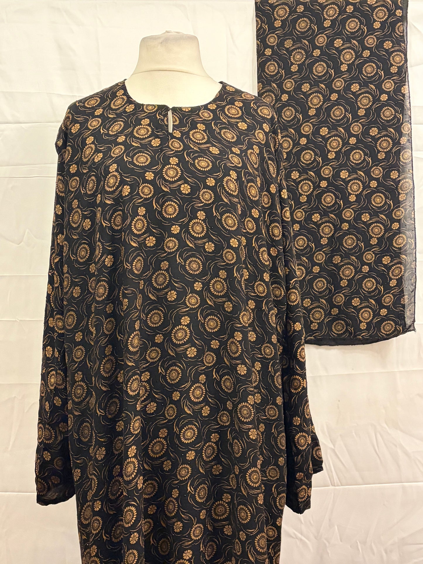 Black fabric with gold paisley pattern on a white background