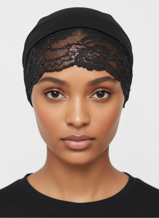 A close-up of a model wearing a black lace head covering or cap against a light gray background.